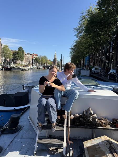 This vibrant photo captures two people enjoying a sunny day on a canal boat in Oudeschans, Uilenburg, Amsterdam